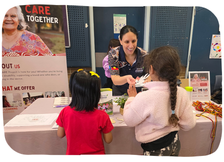 CARE Project team member chatting with a family at a community information stall.